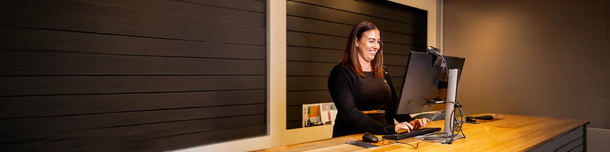One of Queensland Country Bank’s Money Mentors standing at a computer workstation inside a modern bank branch.